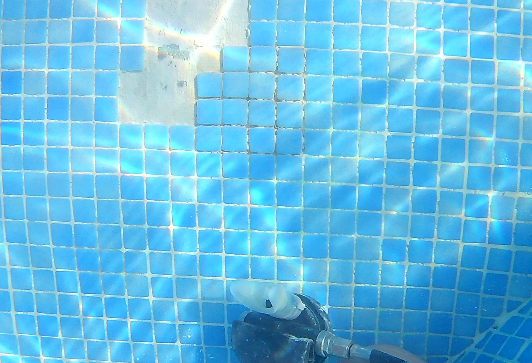 Missing blue mosaic pool tiles photographed before repair