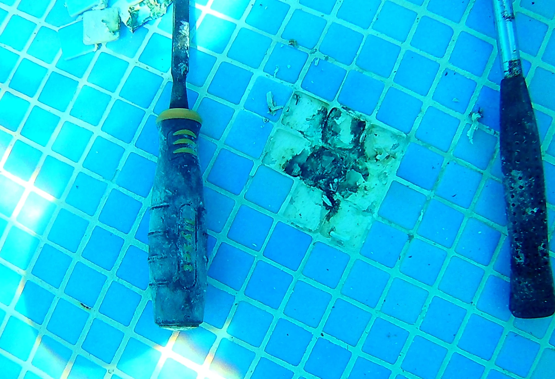 Exposed localised rust repair with tools on a blue tiled pool floor